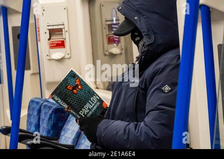 London, UK. 5th Jan, 2021. Reading a story of a great escape - The underground is still fairly busy despite the new national Lockdown, Stay at Home, instructions. Most travellers wear masksas they are already mandatory. Credit: Guy Bell/Alamy Live News Stock Photo
