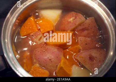 Boiled red potatoes and yams in a stainless steel cooking pot. Stock Photo