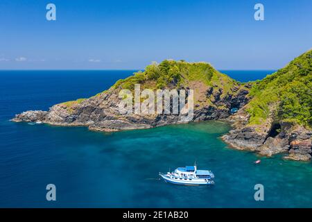 Aerial drone view of boats around a beautiful, remote tropical island in a blue ocean Stock Photo