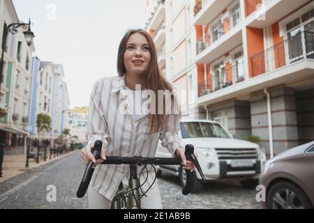 Happy beautiful woman riding her bicycle on city streets Stock Photo