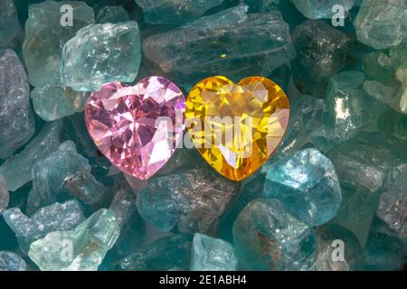 pink amethyst gem and Yellow gem in heart shape on raw sky blue gemstones Stock Photo