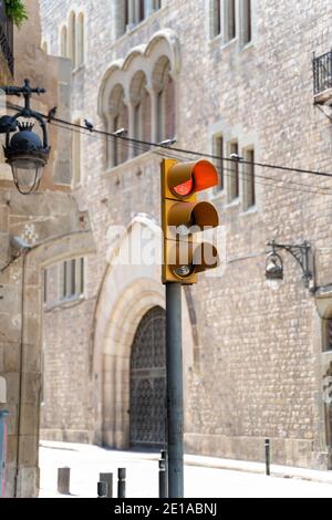 Yellow traffic light showing red on street with medieval buildings in Barcelona Stock Photo