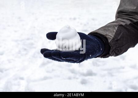 Snowball in the form of a cake on a hand in a mitten, winter outdoor games. Season mood snowy weather Stock Photo