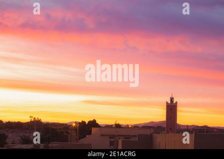 A vibrant sunrise over the village of Merzouga, the gateway to the Erg Chebbi desert dunes in Morocco. Stock Photo