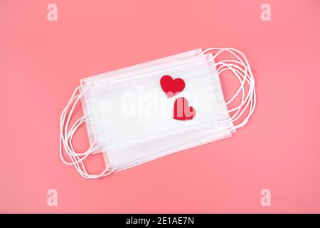 Two red hearts on white medical masks. Top view, with space to copy. Stock Photo