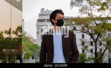Young latin man wearing a face mask for protective reasons during the covid 19 pandemic Stock Photo