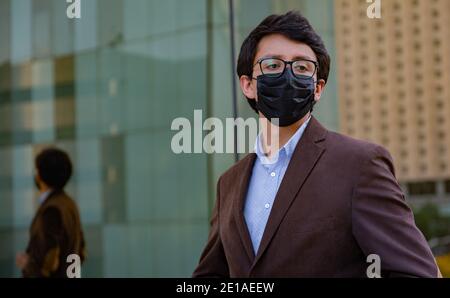 Young latin man wearing a face mask for protective reasons during the covid 19 pandemic Stock Photo