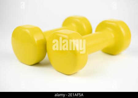 Two yellow dumbbells on white background Stock Photo