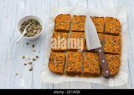 Carrot bars with oatmeal, dried apricots, seeds and honey on a light blue background, selective focus, top view. Healthy energy snack Stock Photo