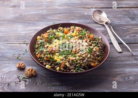 Lentils with dried apricots, nuts, fried onions and parsley. mshosh of lentils, an Armenian dish. delicious healthy national dish. on a wooden table Stock Photo