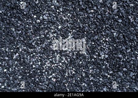 Black sand texture. Full frame macro photography of dark rough sand surface. Abstract pattern background. Close-up design element. Top  view. Stock Photo