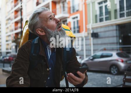 Senior deliveryman riding bicycle, using smart phone to navigate Stock Photo
