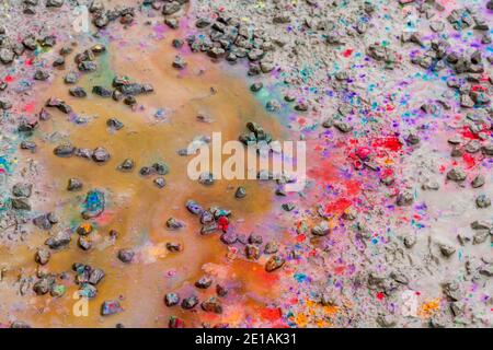 full frame abstract shot showing various colorful paint splatters on muddy ground Stock Photo