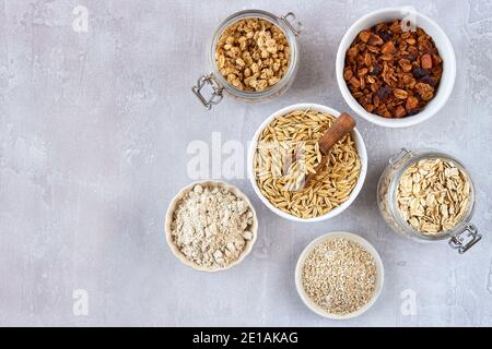 Oat products assortment in bowls. Granola, rolled oats, bran , flour and raw oat seeds . Top view Stock Photo
