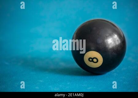 A very used eight ball closeup over the pool table Stock Photo