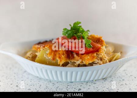 Closeup shot featuring delicately set side dish, garnished with tomatoes, and green leaves on top, with the plate set on marble shelf Stock Photo