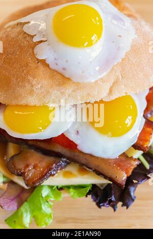 Closeup shot of mouthwatering sandwich, made of three fried quail eggs, and other stuffing including vegetables, taken from above Stock Photo