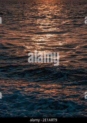 A detailed texture created from the waves and ripples in the ocean water with sunset shines reflected on its surface Stock Photo