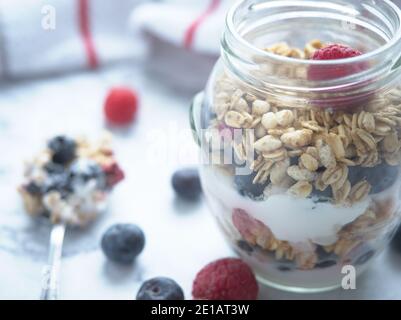 yogurt parfait with granola blueberries raspberries in a jar, spoonful next to jar Stock Photo