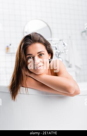 young smiling woman looking at camera while taking bath at home Stock Photo