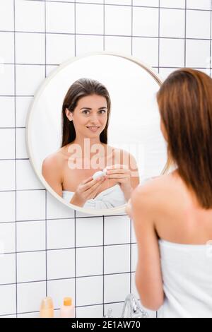 smiling woman holding dental floss near mirror in bathroom, blurred foreground Stock Photo