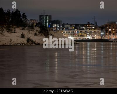 Helsinki / Finland - JANUARY 5, 2021: Beautiful night cityscape of Sompasaari residential district casting reflections on the thin icecap on the water Stock Photo