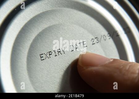 Finger pointing at the expiry date on canned food Stock Photo