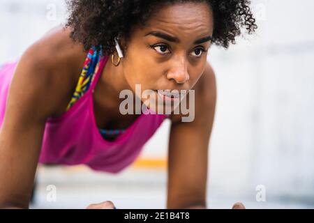 Afro athlete woman doing pushups outdoors. Stock Photo