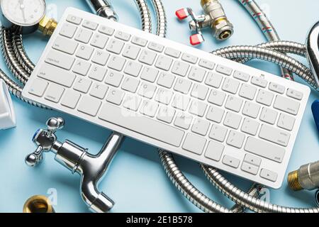 Plumbing items and computer keyboard on color table Stock Photo