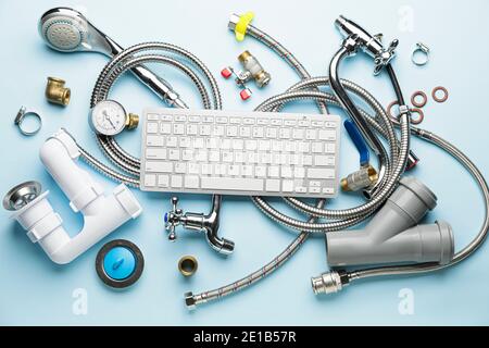 Plumbing items and computer keyboard on color background Stock Photo