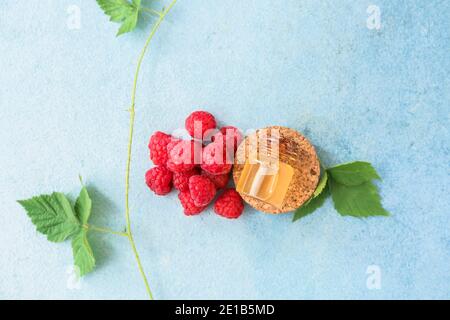 Bottle of raspberry essential oil on color background Stock Photo