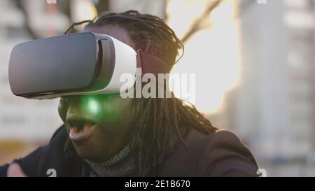 Happy african american black businessman enjoying virtual reality. Wearing VR headset or 3d spectacles while walking outside. High quality photo Stock Photo