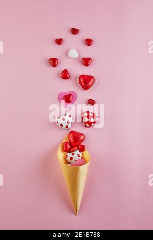 Valentine's Day card with candy hearts flying out of an ice cream cone on a pink background. Top view with a place for your greetings Stock Photo