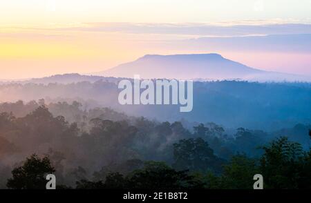 Aerial view over mountain range covered with fog and cloud at sunrise. Stock Photo