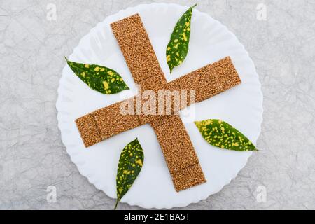 Til sakri or Tilgul an Indian traditional popular sweet made out of Sesame seeds and jaggery. Famous Sankranti festival dessert arranged on white plat Stock Photo