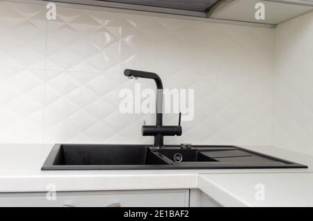 Black sink with faucet in light, white classic kitchen close-up Stock Photo