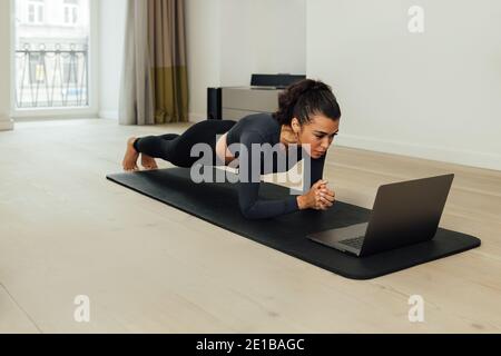 Young fit woman doing plank on mat at home Stock Photo