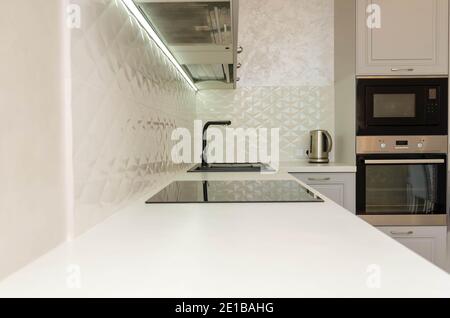 Beautiful interior of a classic kitchen in light gray and white colors with led lighting Stock Photo