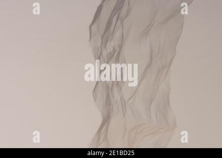 Beige abstract background with piece of crumpled transparent fabric close up. Stock Photo