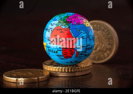 Money rules the world globe miniature mini earth with coins. Concept. Stock Photo