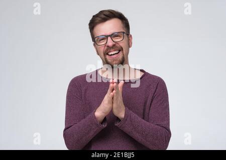 Smiling young man with beard and glasses looking at camera. Studio shot. Stock Photo