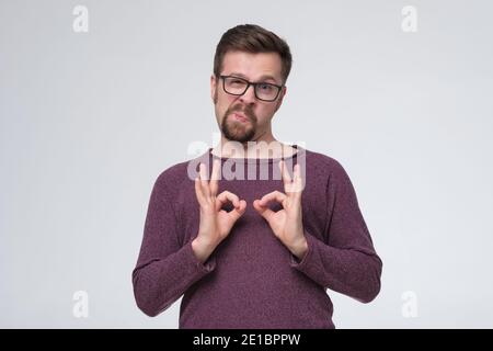 Young handsome man with glasses and beard smiling positive doing ok sign. Successful positive facial expression. Stock Photo