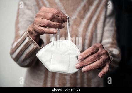 close-up of older womans hands holding face mask Stock Photo