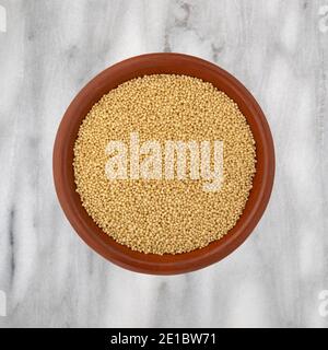 Top view of amaranth seeds in a small bowl on a gray marble countertop. Stock Photo