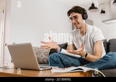 Picture of happy smiling handsome man indoors at home using laptop computer and studying Stock Photo
