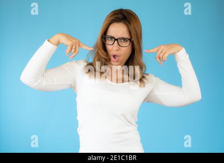 Indignant discontent young female points at herself, asks why its her duty, frowns face in displeasure, expresses disagreement, wears white sweater, i Stock Photo