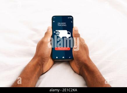 Black man using smartphone with delivery tracking app Stock Photo