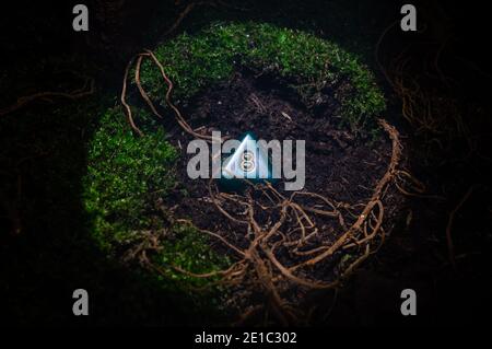 Close-up RPG scene of a 8-sided die in the dirt with roots and moss  in a circle of light. Stock Photo