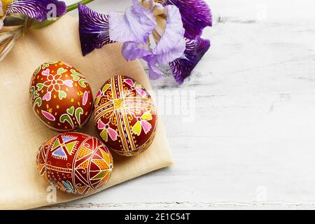 Three handmade Easter eggs decorated with wax-resist dyeing technique. Ukrainian pysanka on white shabby wooden background with empty space for text Stock Photo