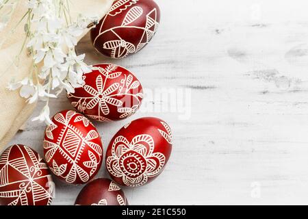 Red and white handmade Easter eggs. Ukrainian pysanka decorated with wax-resist dyeing technique. White wooden background with copy space for text Stock Photo